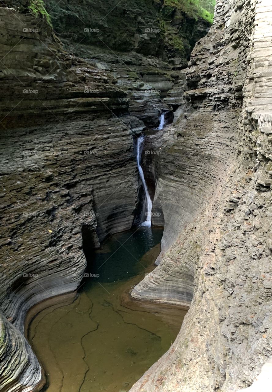 Beautiful waterfall curving around with the rock surrounding it diving into another pool of water. 