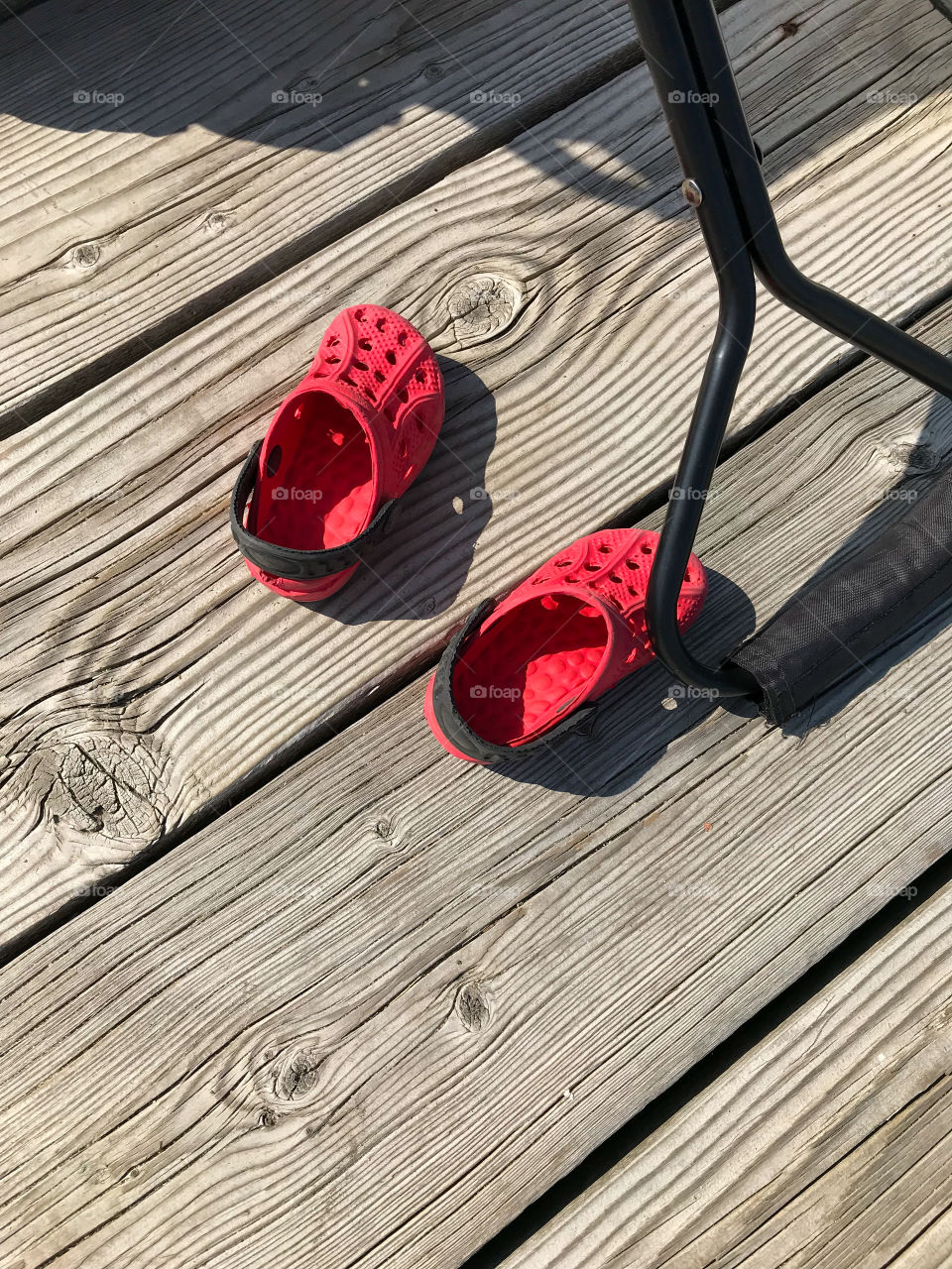 POV & pop of RED! Tiny little red rubber shoes left on the dock next to a wagon to be reclaimed after a day out boating in the beautiful sunshine out on the lake. 