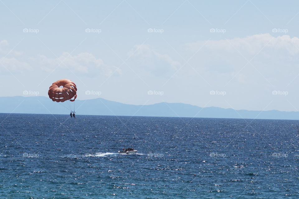 parasailing. parachute carrying people while boat is pulling them