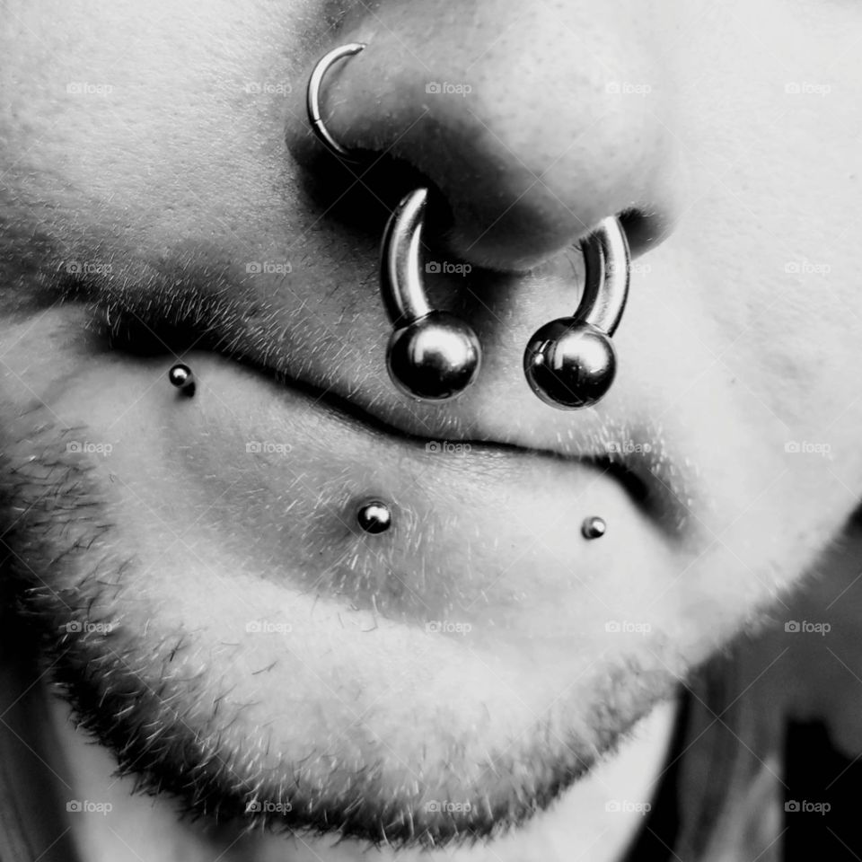 man with facial piercings in black and white