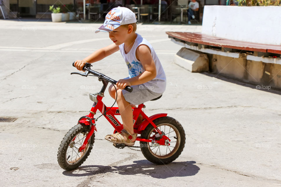 A boy's riding his red bicycle