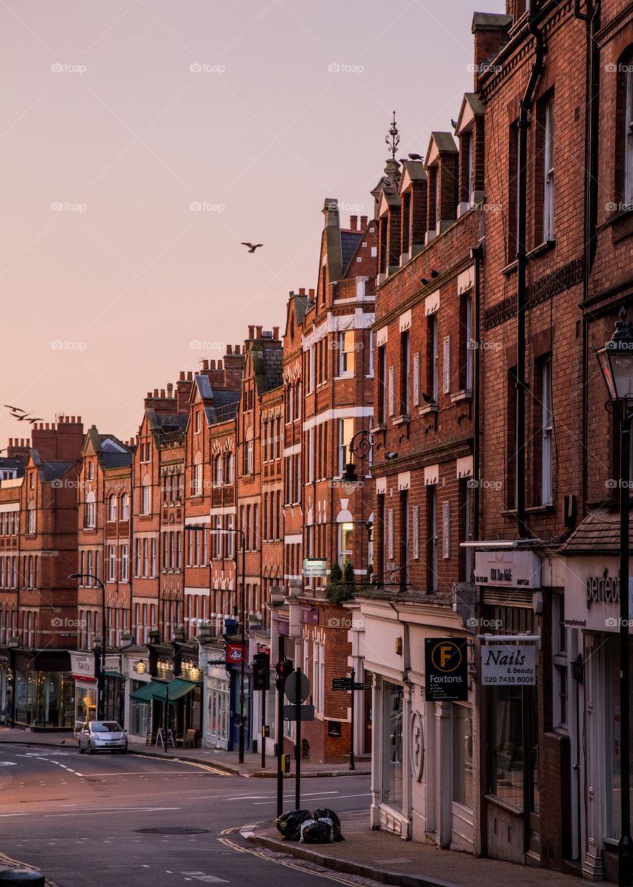 A beautiful sun behind buildings and reflecting delicately on the brick flowing down the city. 