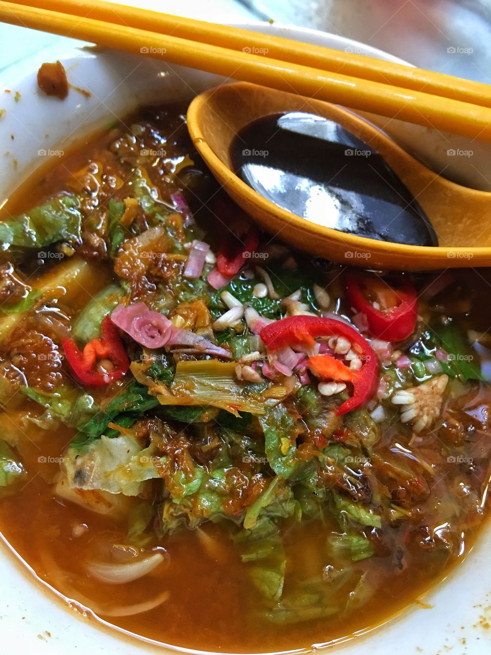 "Asam Laksa" is a Malaysian street food consisting of thick rice noodles similar to udon, cooked in a spicy sweet and sour tamarind and fish broth and garnished with chopped chillies, raw onions, mint leaves and a thick brown sauce made from fermented shrimp paste