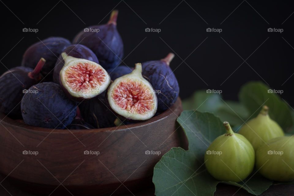 Purple and Green figs with wooden bowl and fig leaves 