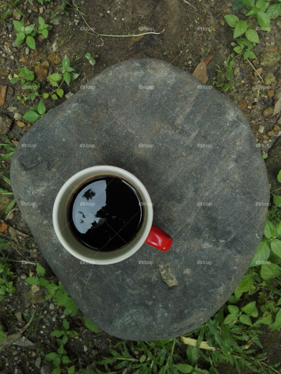 A red coffee cup on a stone.
