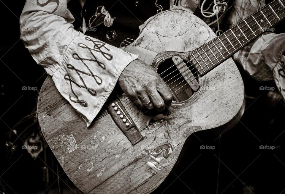 Beat up, old acoustic guitar played by weathered hands.