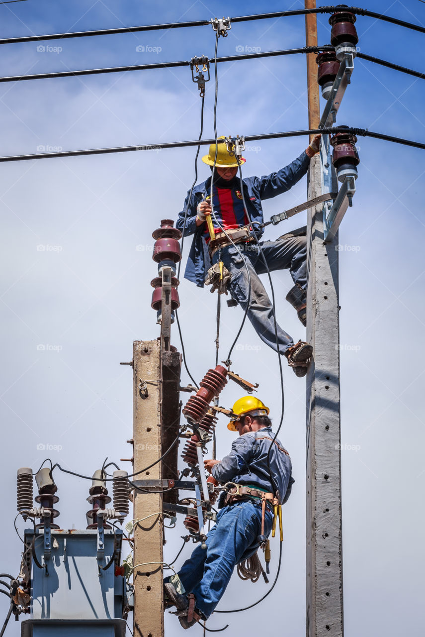 Electrician working together on the electricity pole to replace the electrical insulator