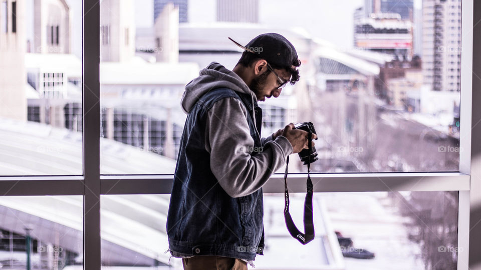 male hipster photographer models as he takes photos of beautiful urban city skyline