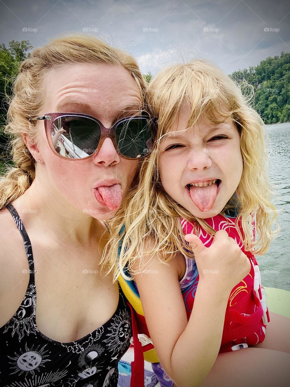 Mother and daughter being silly while enjoying the hot summer day on the lake 