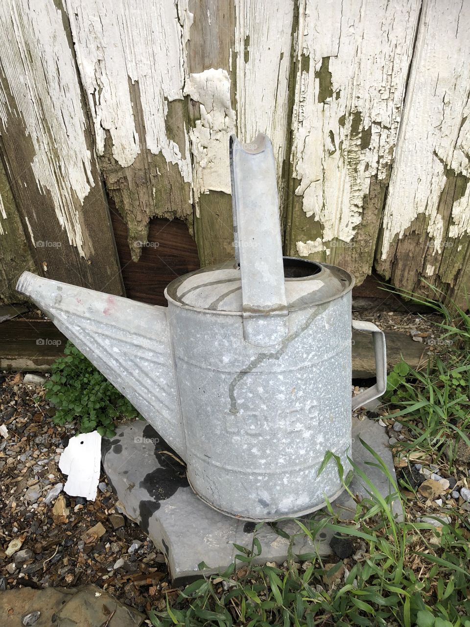 Vintage antique watering can against old barn 