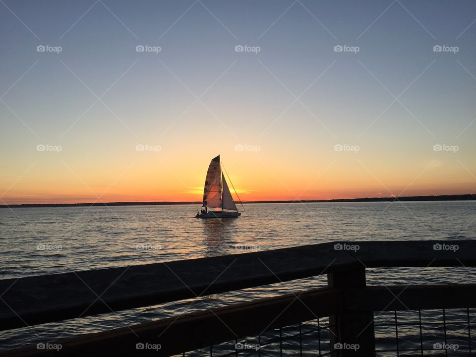 Golden Sailboat. Watching the sunset as sailboats float on by