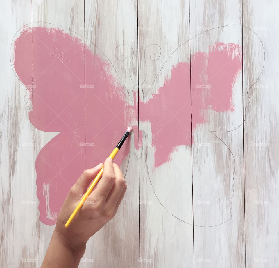Painting a butterfly on rustic white wood backdrop