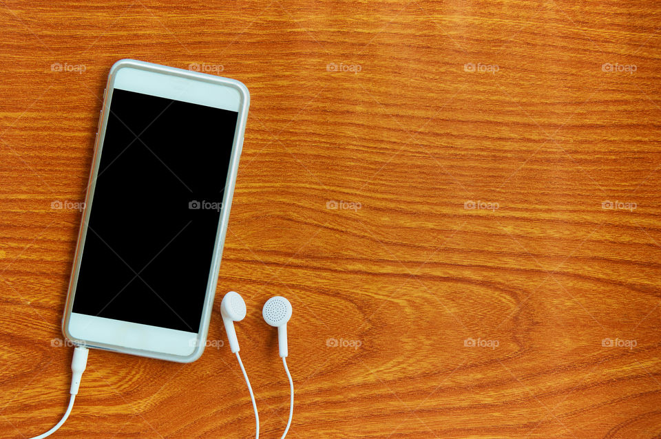 Smartphone and headphones on brown background 