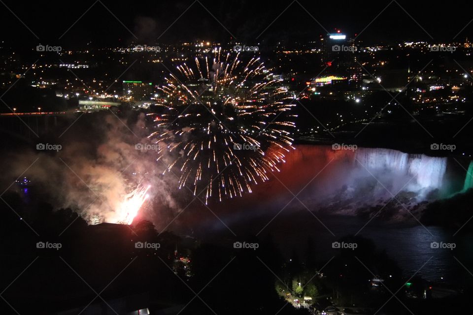 Fire works explode on warm summer night over Niagra Falls, USA, viewed from Canada