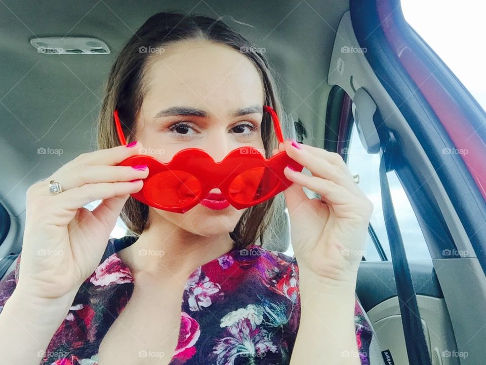 Selfie of woman in the car wearing heart-shaped sunglasses