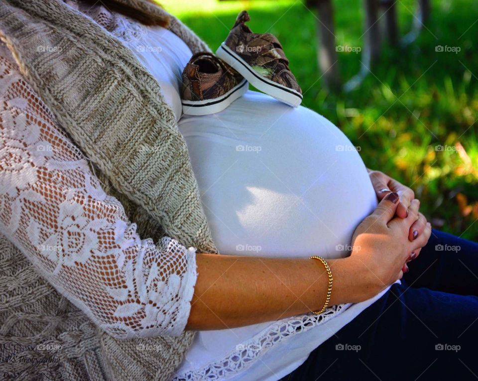 Baby bump. Baby shoes on mama's bump