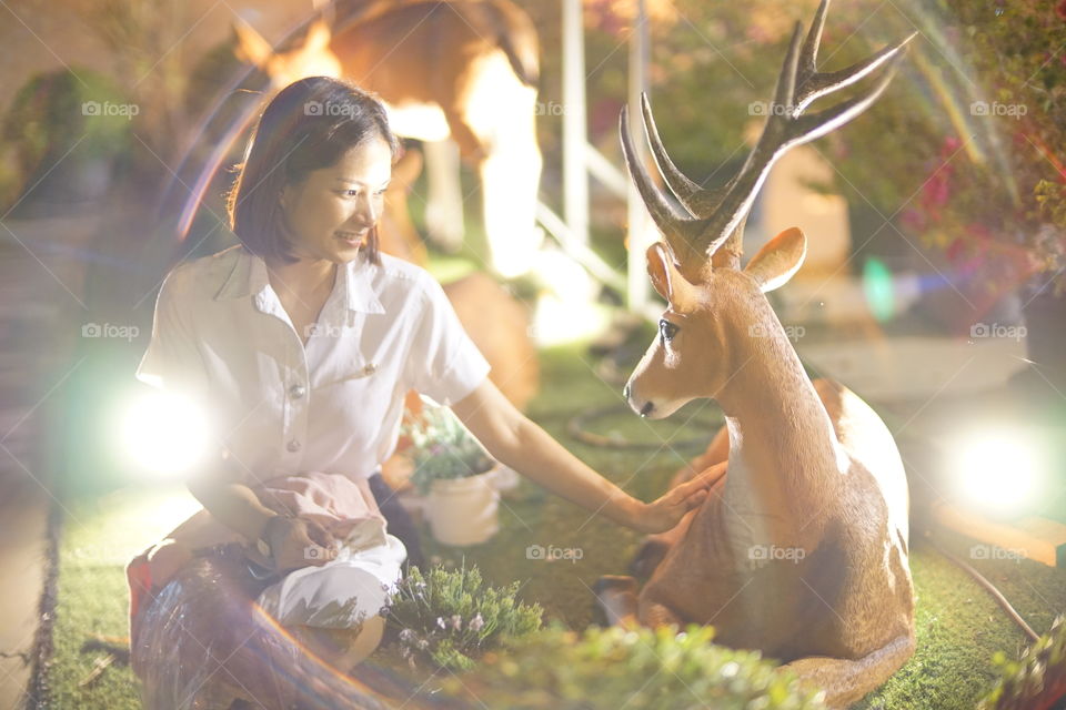 A girl take a small talk with the deer in the jungle 