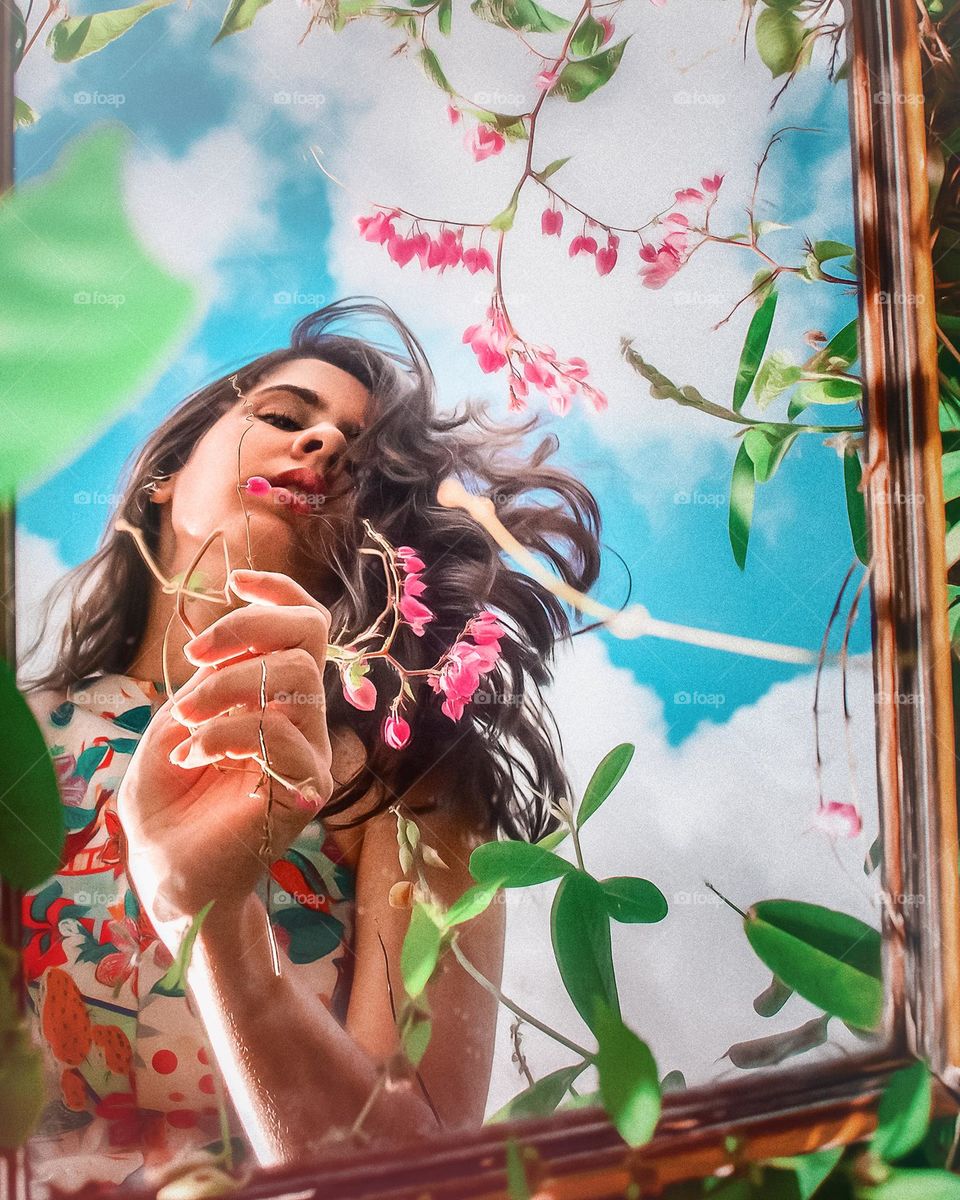 A woman’s reflection with flowers frame and a blue sky.
