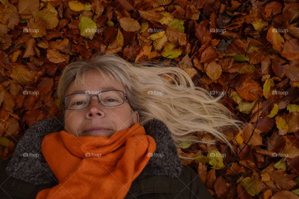 Mature woman lying on dry autumn leaves