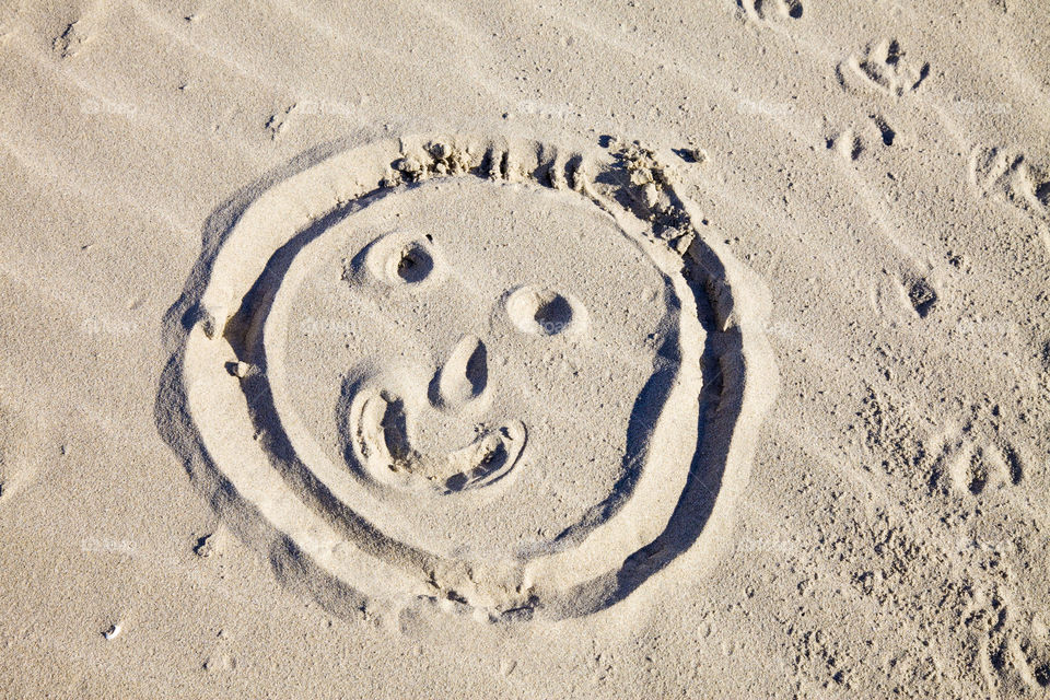 Smiley face drawn in sand at the beach