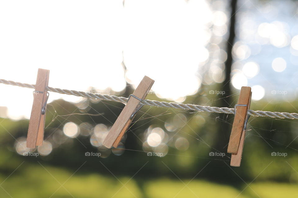 Three's company: a trip of wood clothespins clothes pegs on outdoor white rope line, Imagery for family, love, relationships, fragility, delicate, balance, harmony. Ethereal feel with the Bokeh 