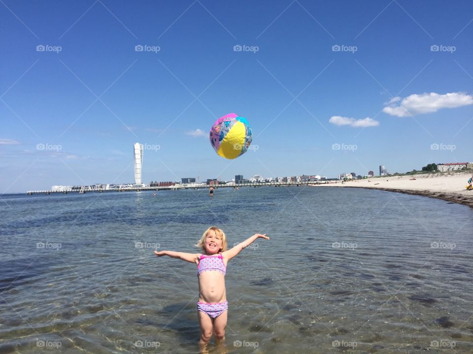 Little girl of three plays with a ball at Ribban beach in Malmö Sweden.