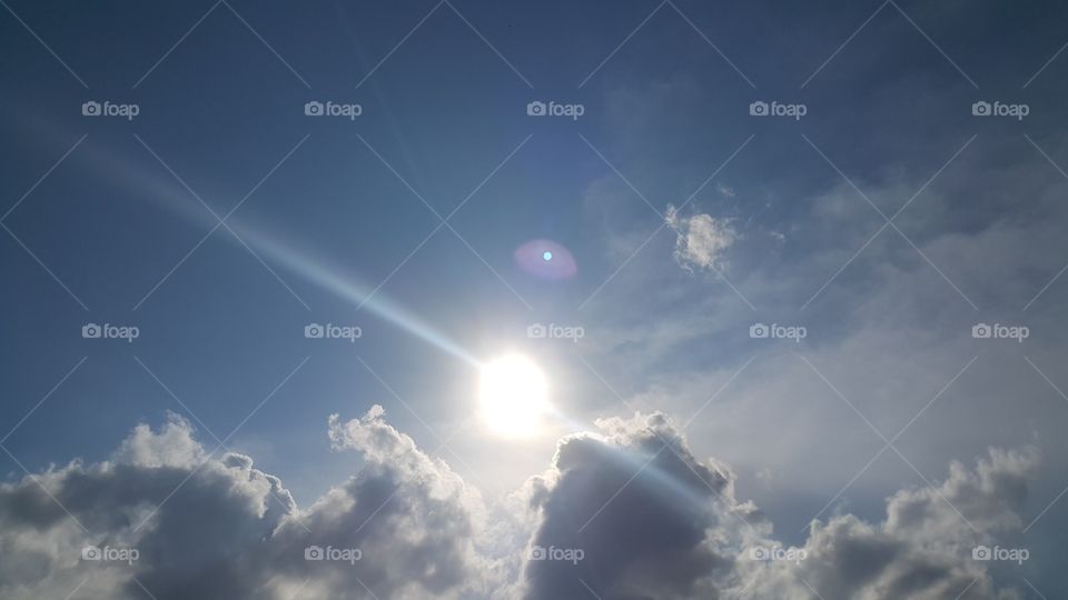 Sun with rays over cloudy sky