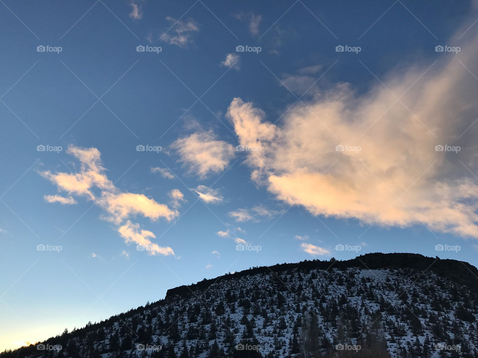 Sunrise over a snow covered butte in Prineville in Central Oregon giving the clouds a red glow against a rich blue sky in the winter. 