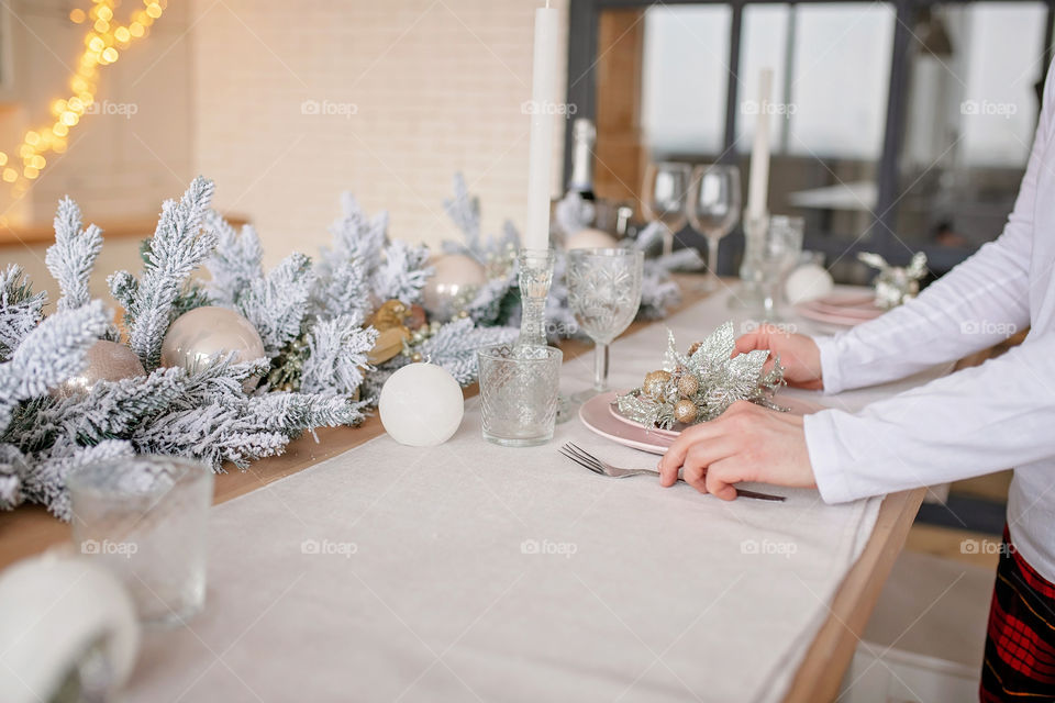 man sets a beautiful decorated winter table for a festive dinner.  Merry Christmas and Happy New Year.