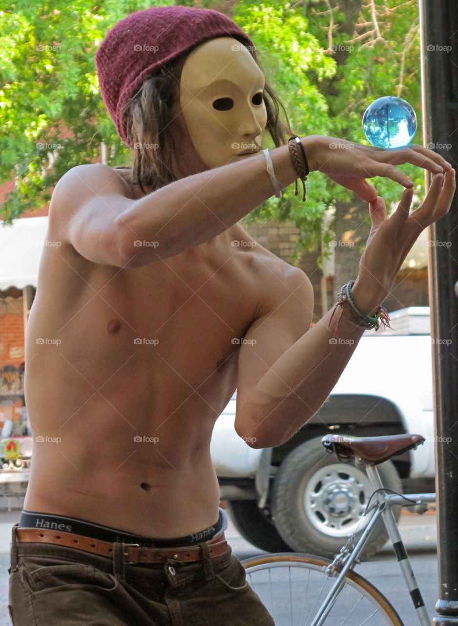 A street artist wearing a mask performing with great skill in downtown Bend in Central Oregon on a summer day. 
