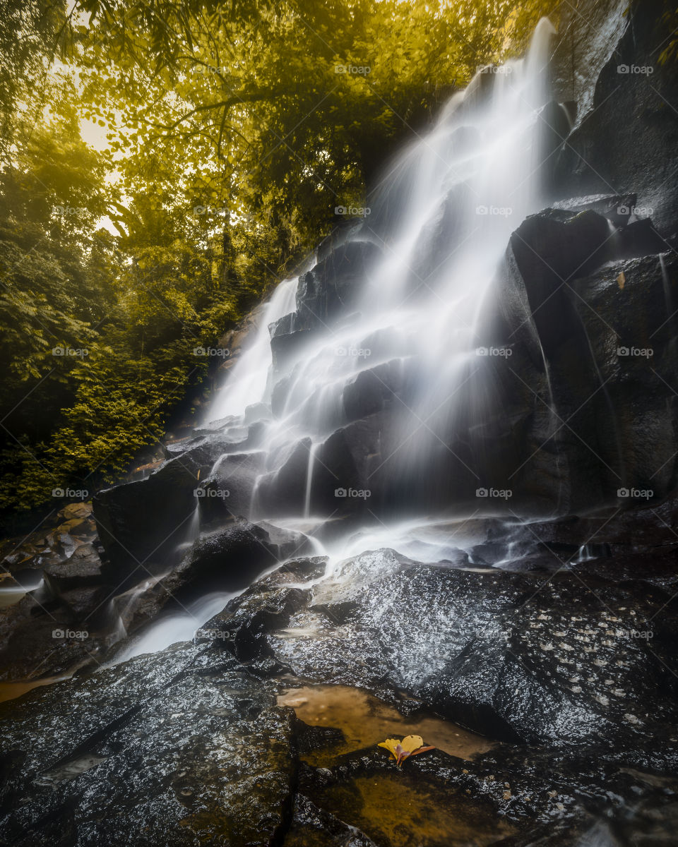 Kanto Lampo Waterfall Bali - Scenic, seasonal waterfall cascading down a stepped rock wall into a shallow wading pool.