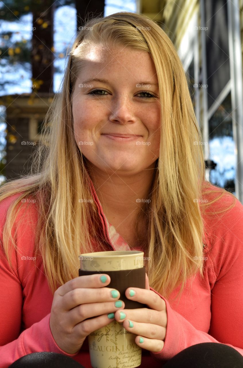 Smiling blonde woman holding ceramic glass