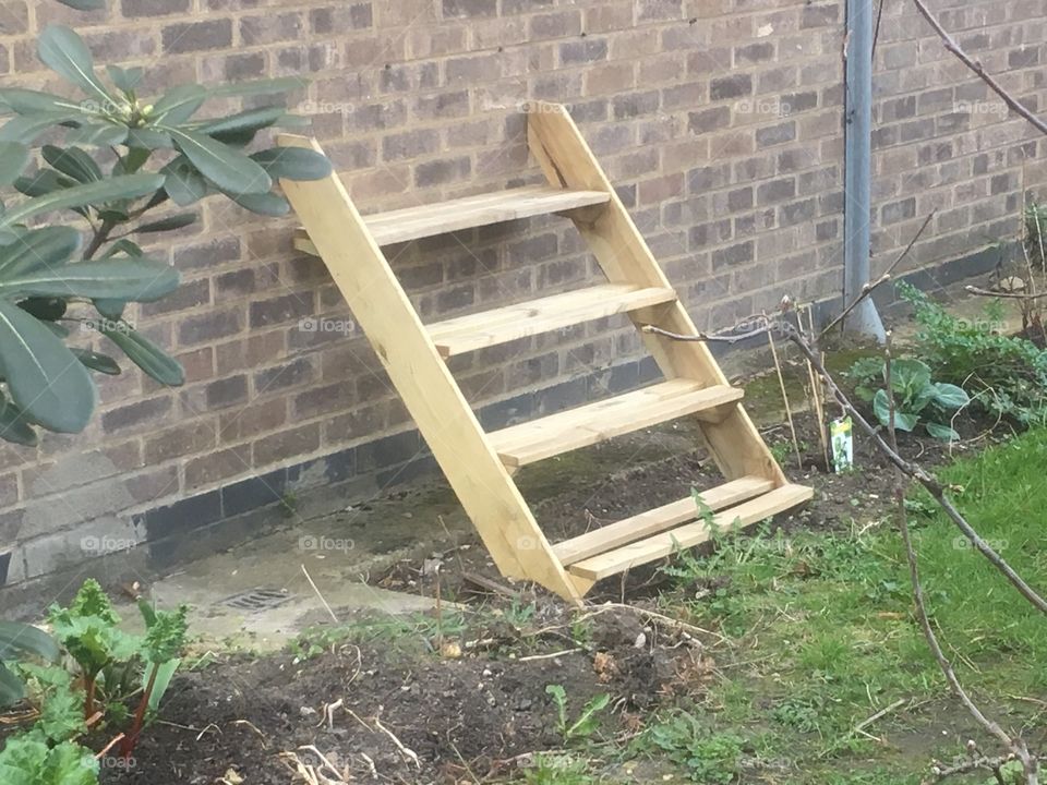 Portable wooden stairs resting against a wall at Balin House, Long Lane, Southwark, in Spring.
