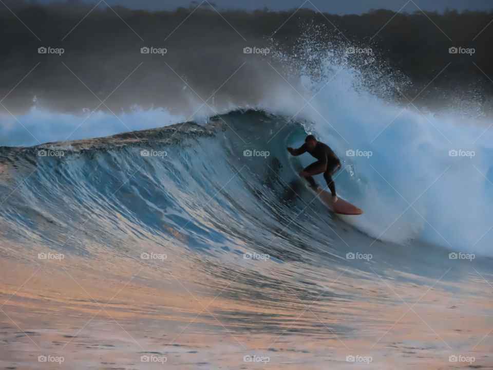 Surfer surfing a barrel wave at sunset