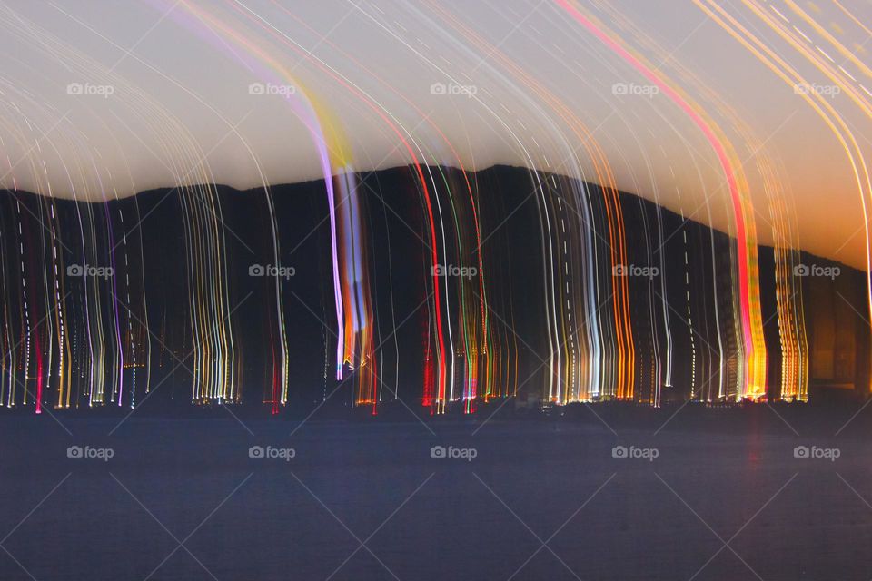 art photo of a distant city near the mountains releasing streaks of light at a long shutter speed