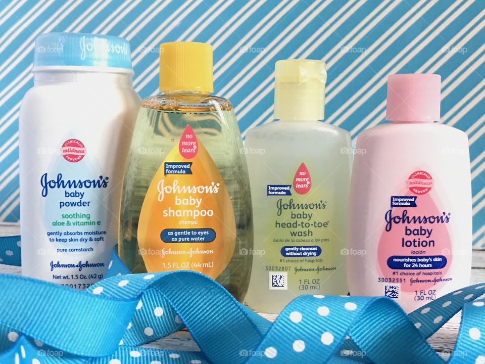 Johnson and Johnson baby lotion, shampoo, head to toe wash and powder on a blue and white background with a blue ribbon 