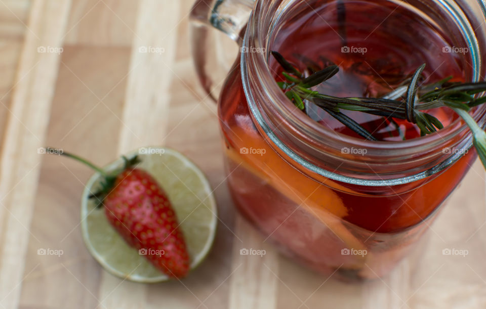 Fresh summer berry and citrus water with rosemary on wood table in vintage glass jar with handle high angle view healthy lifestyle and summer hydration choices food photography 