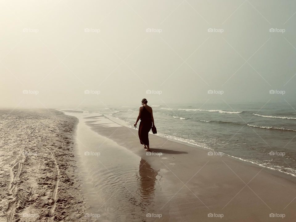 Girl walks on a foggy beach