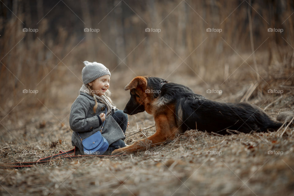 Little girl with German shepherd young male dog walking outdoor at spring day