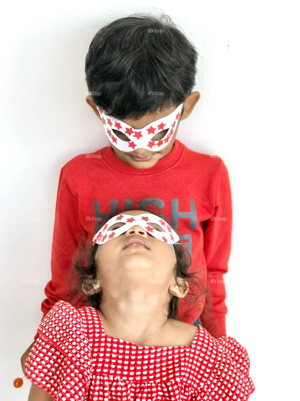 Two kids having fun with hand made party eye masks.