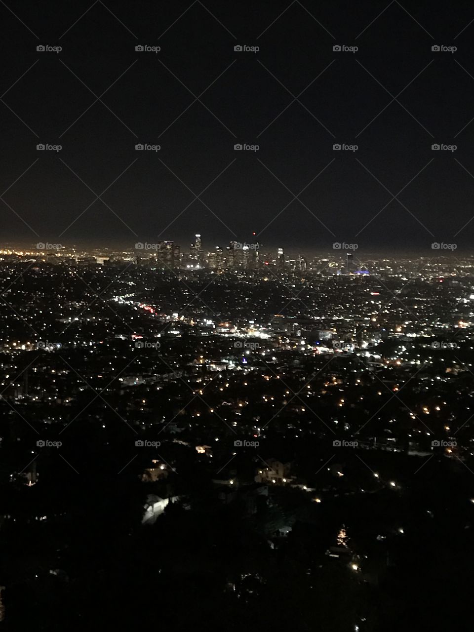The beautifully twinkling skyline taken from the Griffith Park Observatory. The scattered lights give way to a glowing horizon and the night sky.