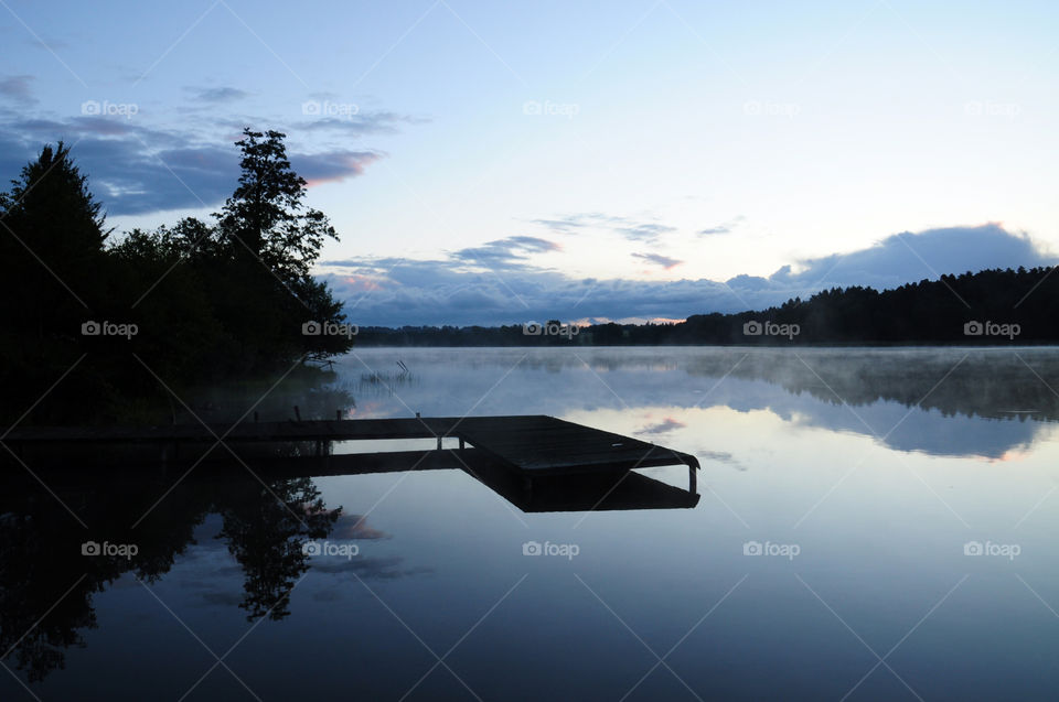 pier and forest silhouette at the lakeside during sunrise at the lake in Poland