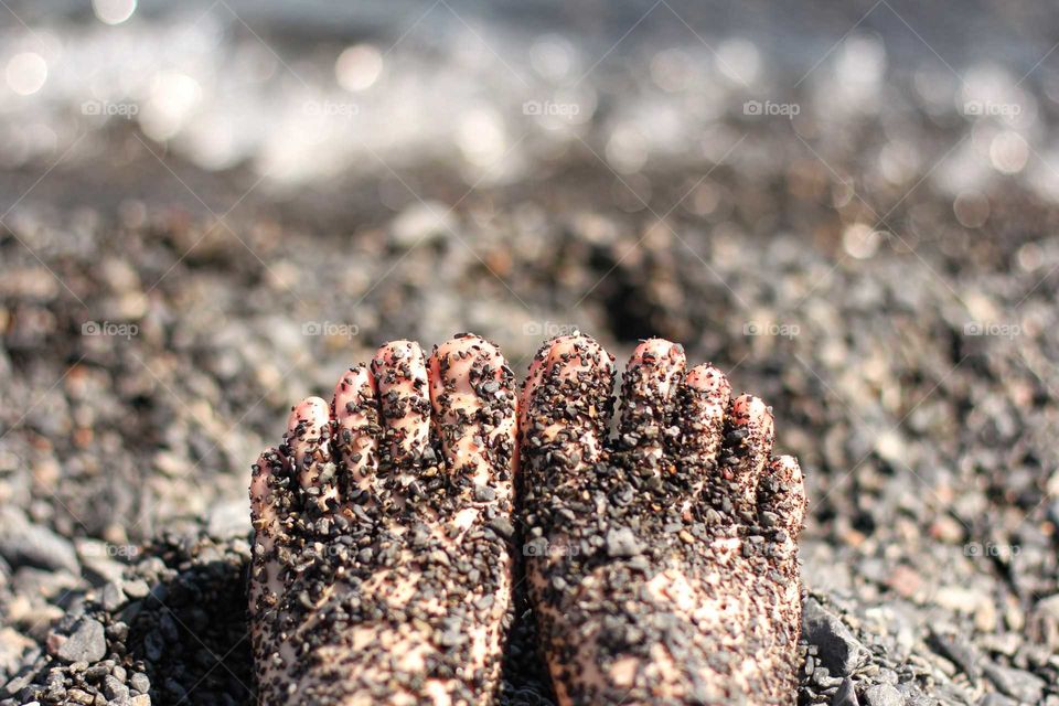 Feet on the beach in black fine sand