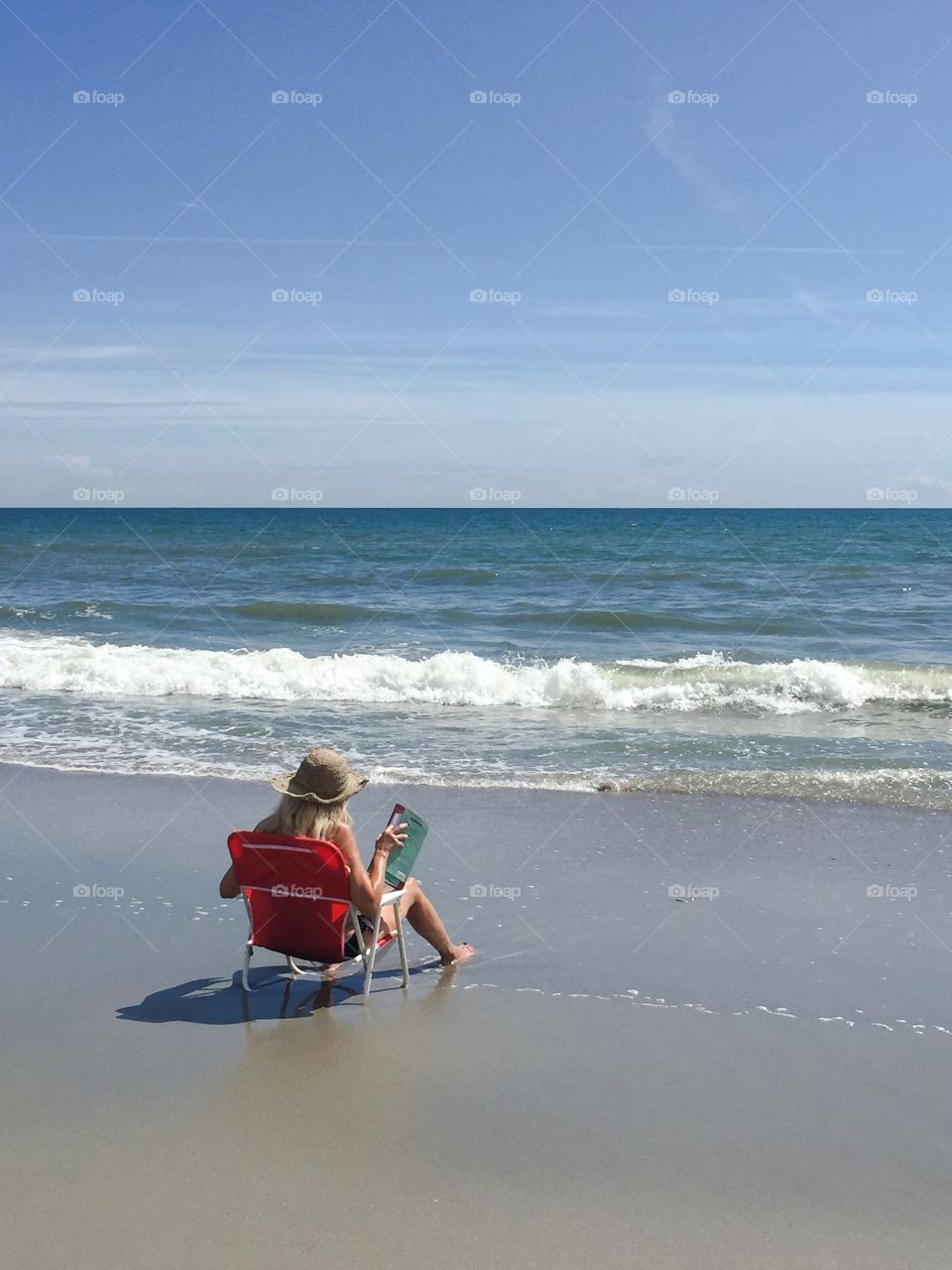 A woman enjoys a good book sitting along the seashore in Myrtle Beach South Carolina.