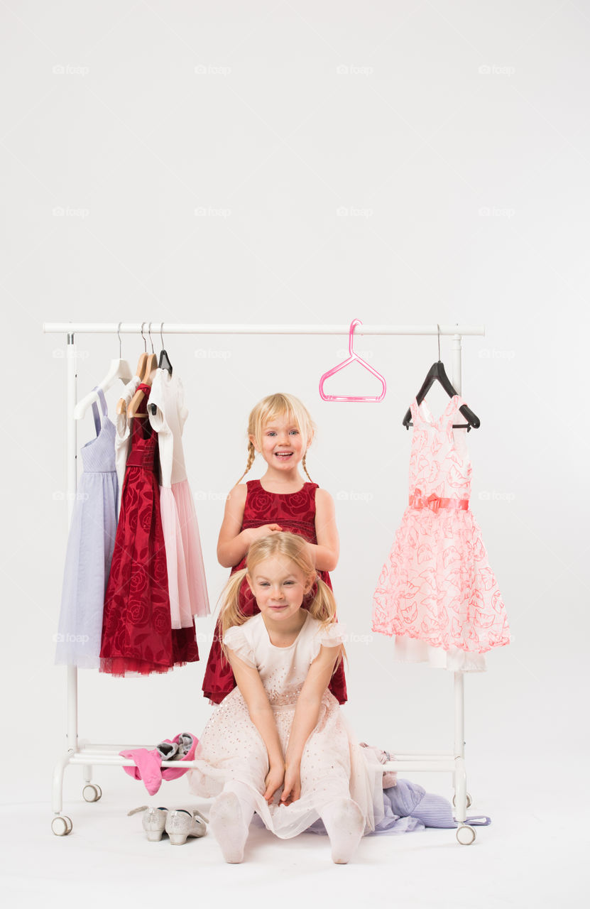 Two cute sisters is posing and playing with clothes and having fun.