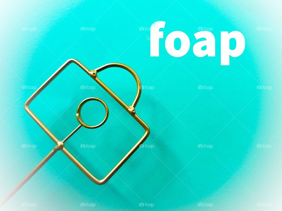 foap flatlay with the foap color in the background and a gold photograph holder in the shape of a camera that looks like the foap logo.