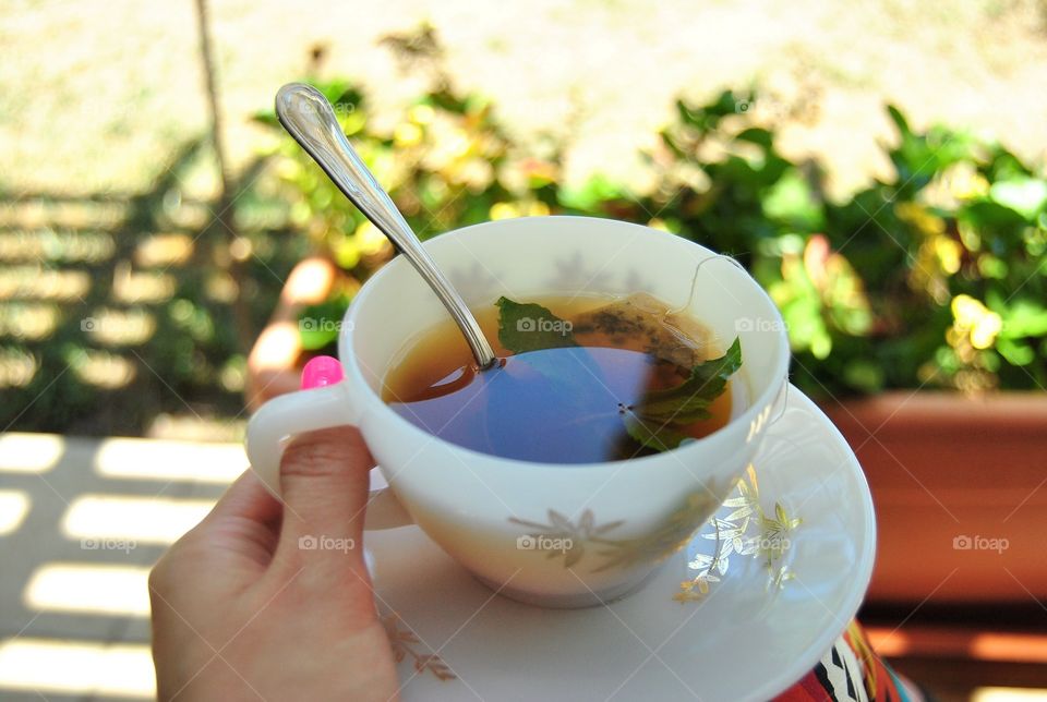 holding a cup of hot tea outdoors in the garden