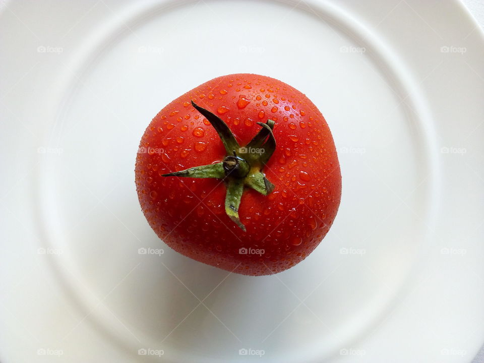 top view red tomato with drops of water on the white plate