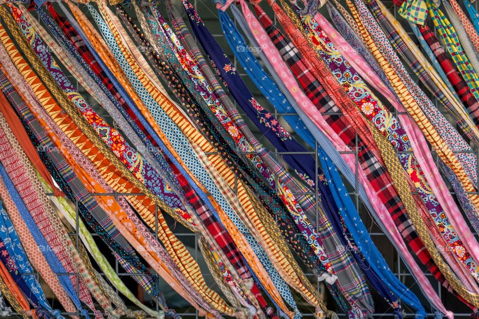 Colorful Rainbow Fabrics Tied Intertwined within a square metal fence