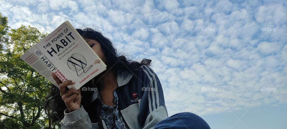 A girl reading a powerful book that is 'the Power of Habit'.